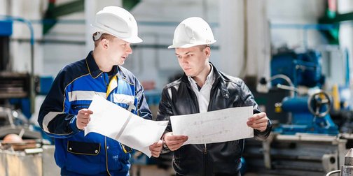 Zwei junge Männer die eine Technische Zeichnung in der Hand halten