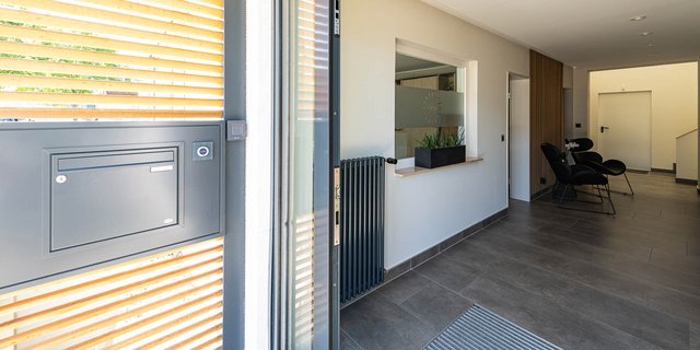 Der Eingangsbereich zeigt eine moderne Tür mit horizontalen Lamellen und einem Briefkasten an der Wand.