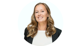 Die Frau mit lockigem Haar strahlt Selbstbewusstsein aus, während sie in einem professionellen Outfit in die Kamera lächelt.